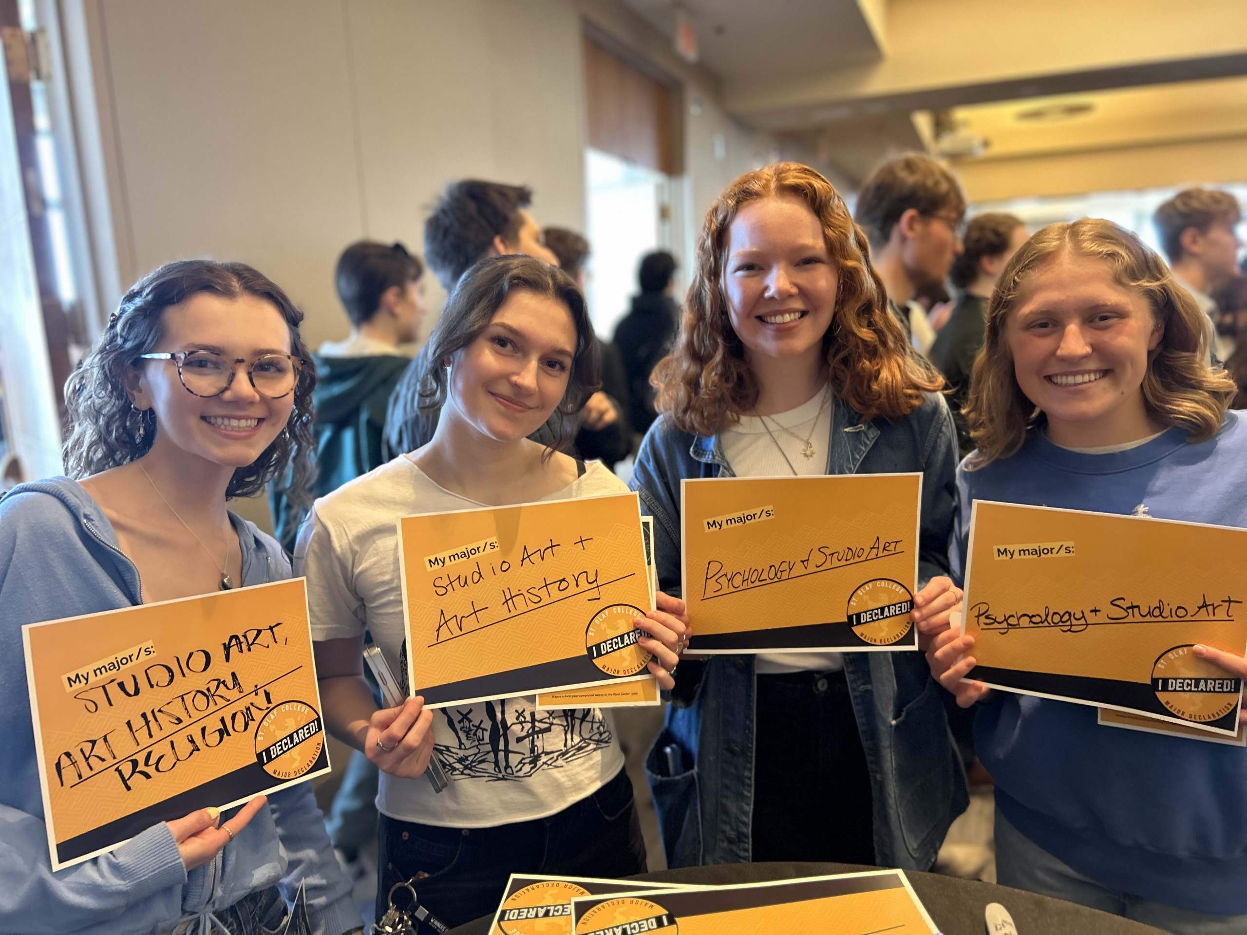 Four students holding papers with their major written
